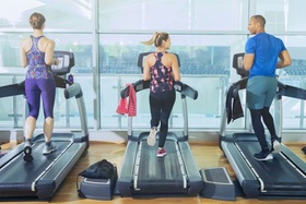 Drei Personen joggen auf Laufband in Fitnessstudio