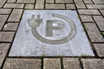 E-Ladesäule Icon in Pflastersteinen auf Parkplatz eingelegt