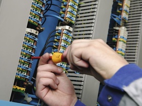 Elektriker mit Schraubenzieher an Schaltkasten, Detail Haende