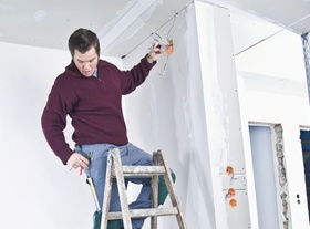 Elektriker steht auf Leiter