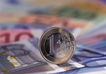 Euromünze rollt auf Scheinen Geld