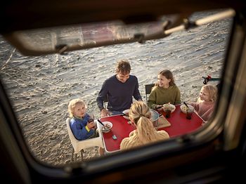 Familie isst Abendessen am Tisch beim Camper Van