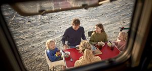 Familie isst Abendessen am Tisch beim Camper Van