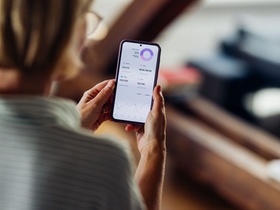 Close-up of a woman using a smartphone to review financial data and analytics at home, focusing on a