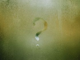 Fragezeichen mit Finger gezeichnet auf beschlagener Scheibe