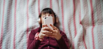 Frau am Handy tippt im Bett