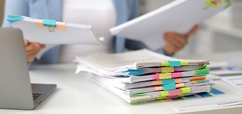frau am schreibtisch sortiert bunte aktenmappen