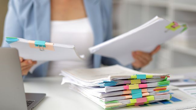 frau am schreibtisch sortiert bunte aktenmappen