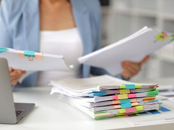frau am schreibtisch sortiert bunte aktenmappen