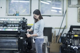 Frau an Druckmaschine in Druckerei