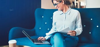 Frau an Laptop auf Sofa