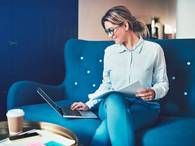 Frau an Laptop auf Sofa