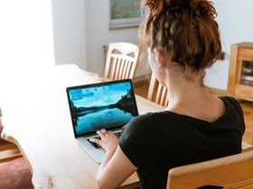 Frau arbeitet am Wohnzimmertisch mit Laptop