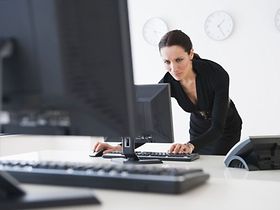 Frau arbeitet an Computer mit Uhren verschiedener Zeitzonen