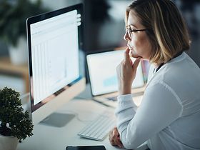 Frau arbeitet an Finanzdaten vor Monitor