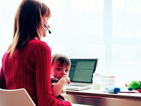 Frau arbeitet im Homeoffice, Kind bastelt