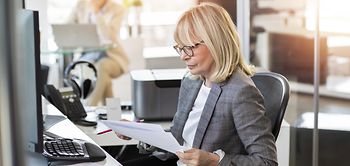 frau arbeitet in lichtdurchflutetem buero mit Anträgen