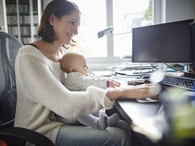 Frau arbeitet mit Baby im HomeOffice