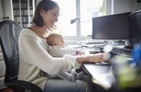 Frau arbeitet mit Baby im HomeOffice
