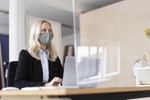 Businesswoman wearing mask using laptop on desk at home during curfew