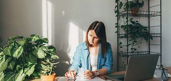 Frau arbeitet zuhause an Finanzunterlagen mit Laptop