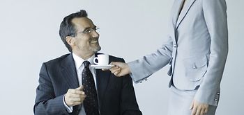 Frau bringt Chef Kaffee und lächelt