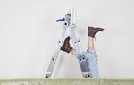 Germany, Cologne, Mature woman fallen down from step ladder during painting living room --- Image by