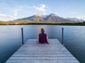 Frau entspannt an See mit Blick auf die Berge