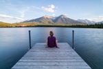 Frau entspannt an See mit Blick auf die Berge