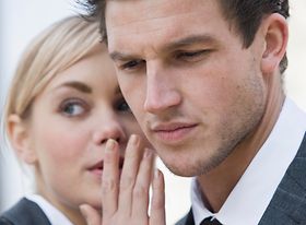 Frau fluestert Mann ins Ohr