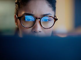 Frau fokussiert vor Monitor frontal