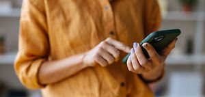 Frau im gelben Tshirt tippt aufs Handy