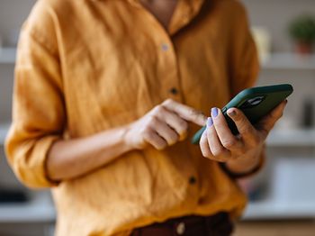 Frau im gelben Tshirt tippt aufs Handy