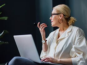 frau im geschaeftsoutfit nutzt sprachfunktion am handy