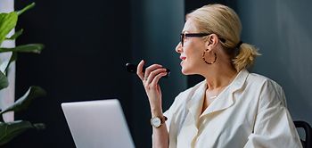 frau im geschaeftsoutfit nutzt sprachfunktion am handy