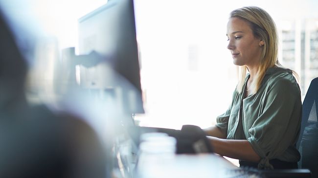Frau in kanzlei arbeitet konzentriert am pc halbtotale