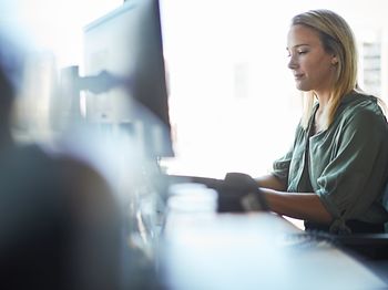 Frau in kanzlei arbeitet konzentriert am pc halbtotale