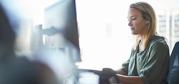 Frau in kanzlei arbeitet konzentriert am pc halbtotale