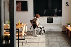 Frau in Rollstuhl fährt in Küche
