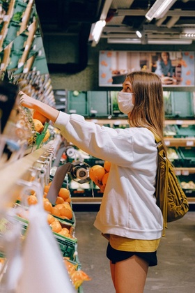 Frau kauft mit Mundschutz Orangen