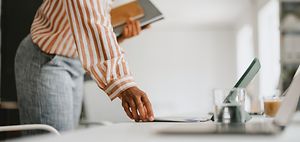 frau legt dokument neben laptop ab