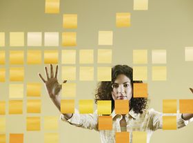Frau lehnt Hände gegen Glaswand mit Post its