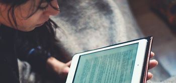 Frau liest zu Hause an einem Tablet