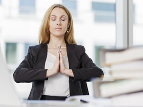 Frau macht am Arbeitsplatz Entspannungsübungen