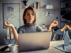 Frau macht Yoga vor Laptop