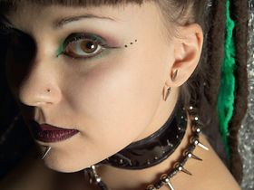 Frau mit Dornen-Piercings an Unterlippe und Ohr, Portraet