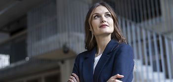 Frau mit eingeschränkten Armen schaut aus dem Fenster