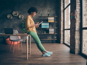Frau mit grüner Hose am Tablet im Büro