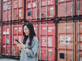 Frau mit Handy vor Containern