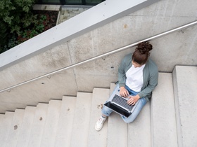 Frau mit Laptop auf Treppe